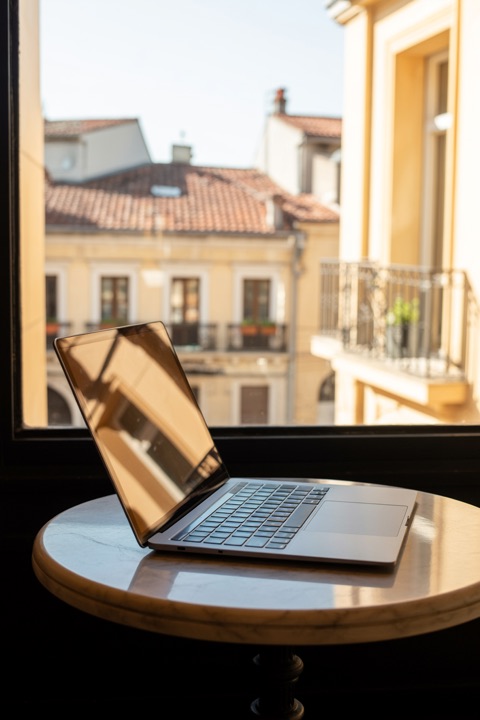 A laptop open in a café, a city street outside