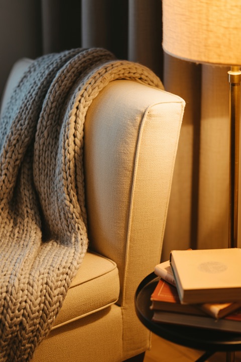 A reading chair with a lamp and a blanket
