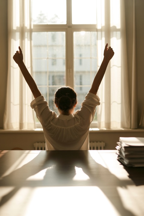 Someone at a desk, arms raised, celebrating