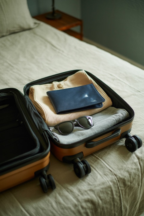 A packed carry-on and sunglasses on a bed